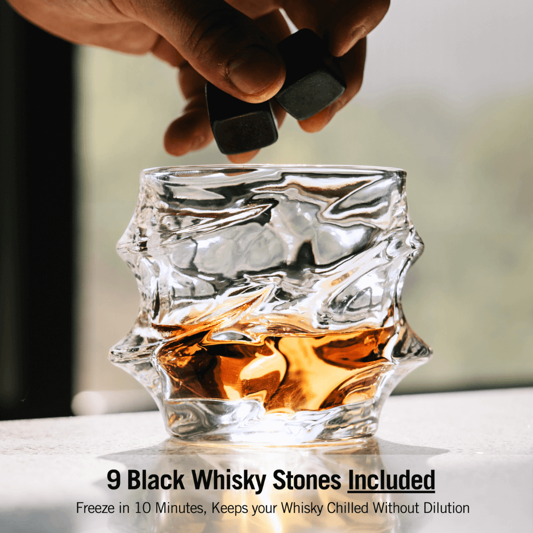 a person adds black whisky stones to a textured glass filled with whisky