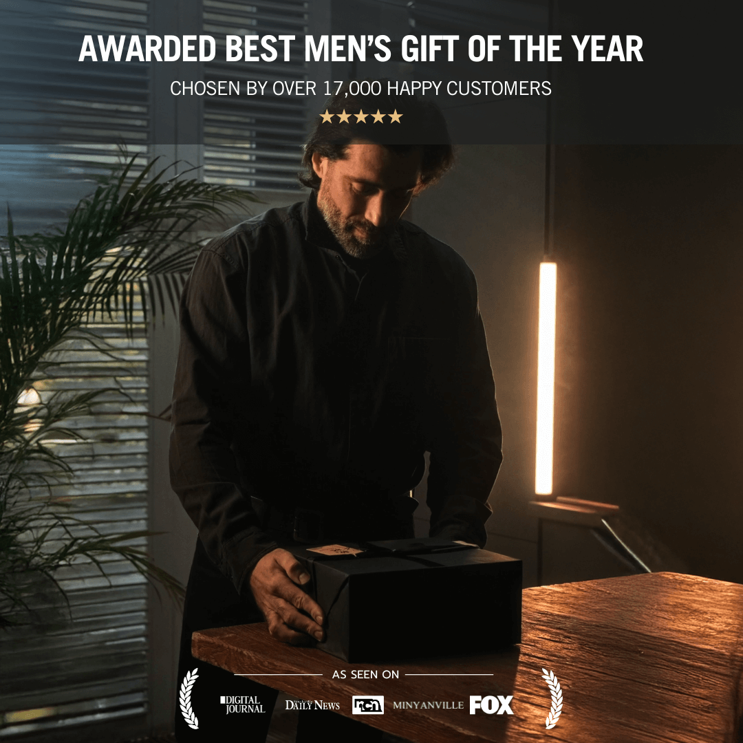 a man places a neatly wrapped black gift box on a wooden table