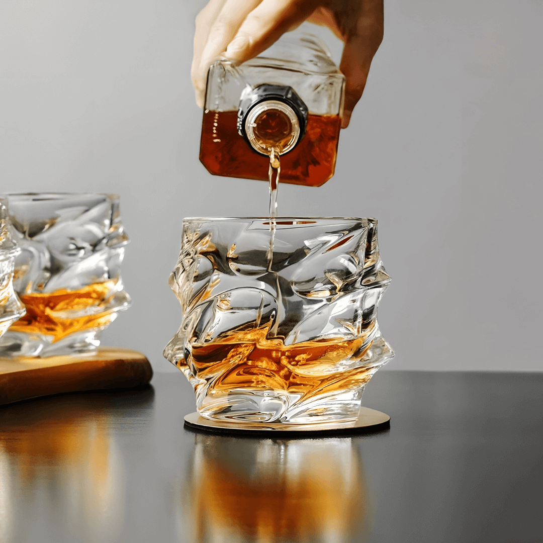 a person pours whiskey from a glass bottle into a crystal galss