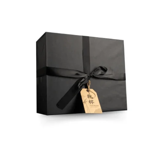 A black gift box with a tied ribbon and a brown tag attached.