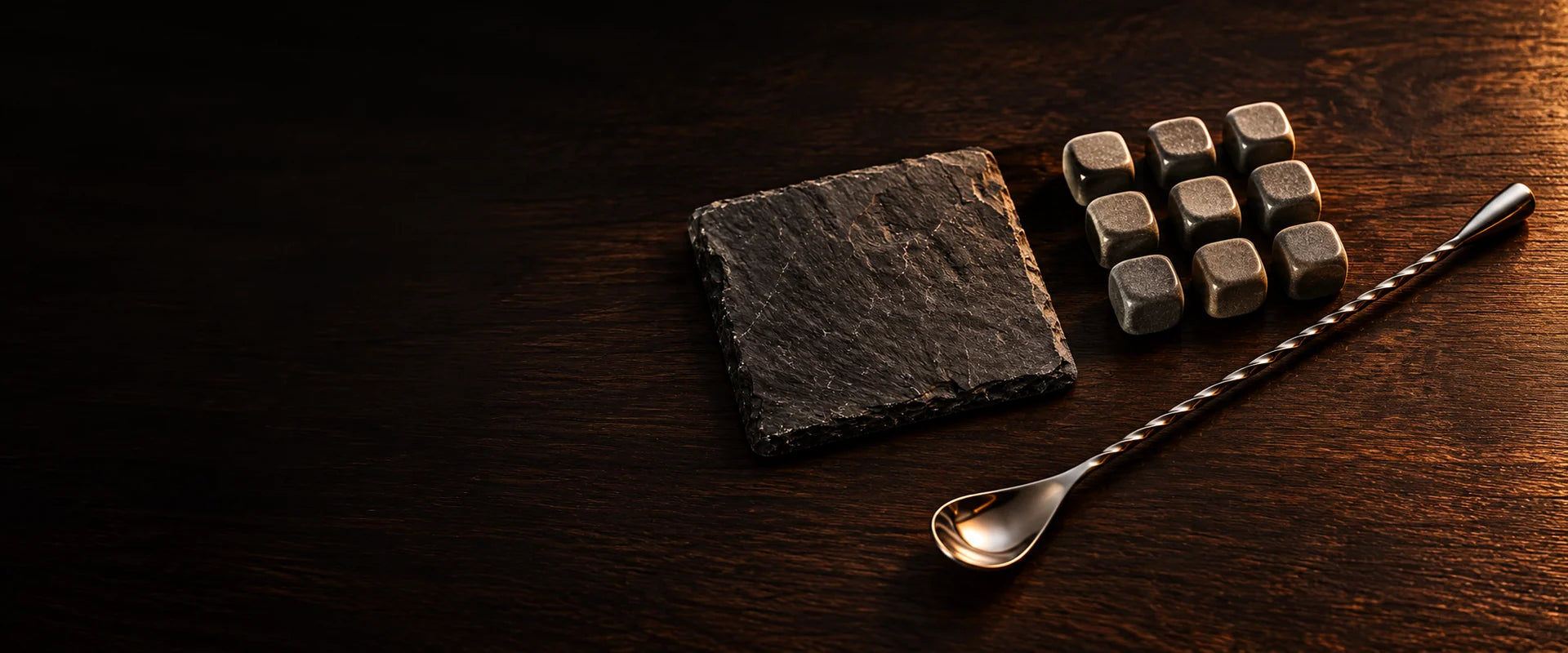 Whisky stones, a dark stone coaster and a spiral mixing spoon